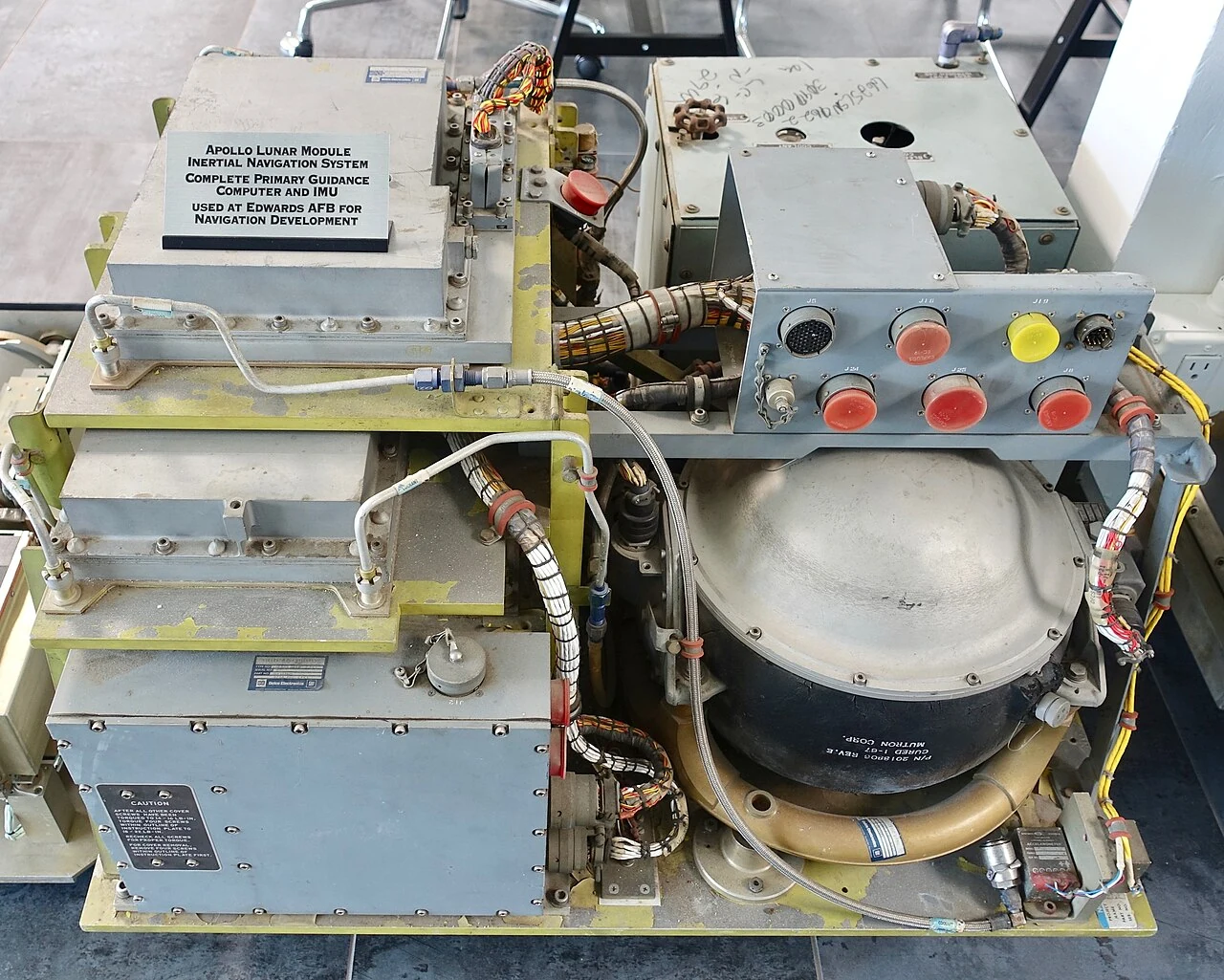 Apollo guidance and navigation hardware, with stacked electronic modules beside a spherical inertial instrument.