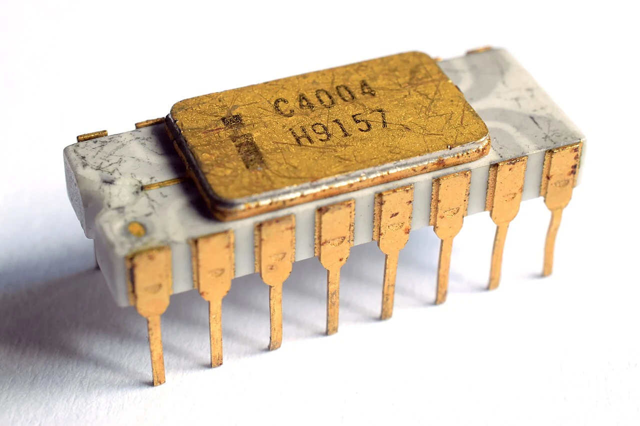 An Intel C4004 ceramic processor package with a gold-colored lid and two rows of pins.